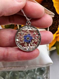 a person holding a necklace with flowers in the center and on it's side