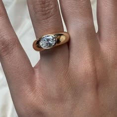 a close up of a person's hand with a diamond ring on their finger