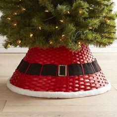 a small christmas tree in a basket with lights on the top and bottom, sitting on a wooden floor