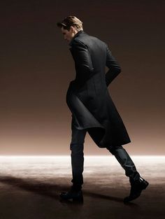 a man in a long black coat is walking