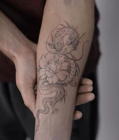 a person with a tattoo on their arm holding onto a snake and flower tattooed on the arm