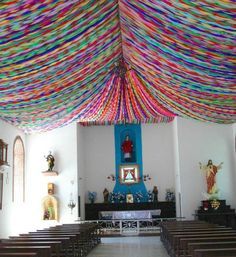 the inside of a church with rows of pews and colorful ribbons hanging from the ceiling