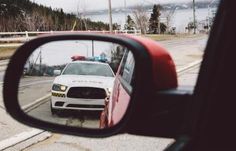 a police car is seen in the rear view mirror