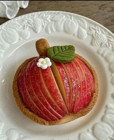 there is a piece of fruit on the plate with leaves and apple slices in it