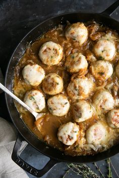 a skillet filled with meatballs and gravy on top of a table