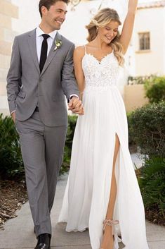 a man and woman in formal wear walking down a sidewalk holding each other's hand