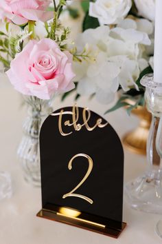 there is a table number with flowers in the vase and candles on the table next to it