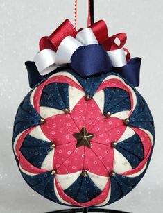 a christmas ornament hanging from a wire with red, white and blue ribbons