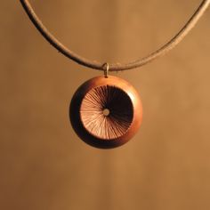 a necklace with a wooden disc hanging from it's side