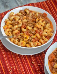 two bowls filled with pasta and meat on top of a red place mat next to a bowl of soup