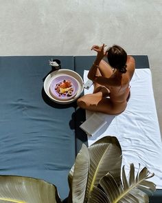 a woman sitting on top of a towel next to a plate