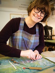 a woman is smiling while working on some artwork