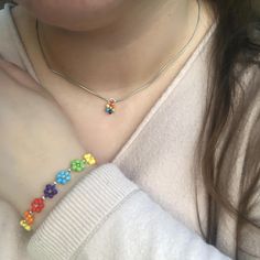 a close up of a person wearing a necklace with flowers on it's arm