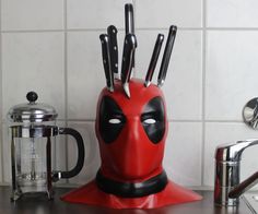 a red deadpool knife holder with knives sticking out of it's centerpiece