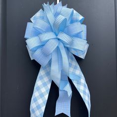 a blue and white bow hanging on the side of a black door with a metal hook