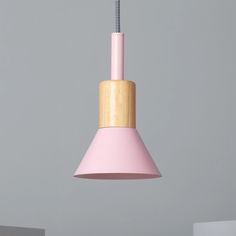 a pink and wooden light hanging from a ceiling fixture in a room with grey walls