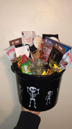 a person's hand holding a black bucket filled with candy