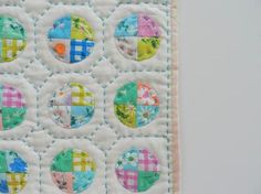 a close up of a patchwork quilt on a white wall with many different colored circles