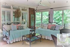 a living room with two couches and a coffee table in front of windows that look out onto the woods