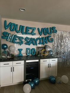 a party room with balloons, streamers and confetti on the wall that says voulez vous she's saying i do