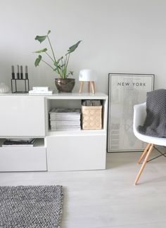 a living room with white furniture and plants on the shelf, next to a chair