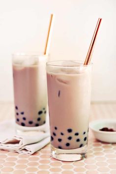 two glasses filled with milkshakes sitting on top of a table