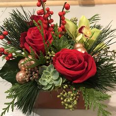 a red rose and greenery arrangement in a wooden box with gold ornaments on it