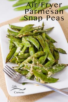 a white plate topped with green beans next to a fork