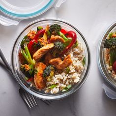 two bowls filled with rice, broccoli and chicken on top of a table