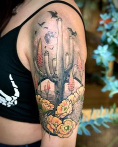 a woman's arm with a cactus and flowers tattoo on her left shoulder, which has birds flying around it