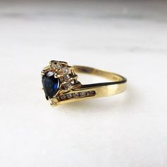 "This is a vintage 14K yellow gold pear sapphire & diamond cocktail ring. The sapphire is 6mm x 4.12mm. There are 19 round diamonds with a total carat weight of .095ct. They have overall G color with I1 clarity. The ring face measures 3/8\" tall x 1/4\" wide. The band is sized at a 7. Total weight of the ring is 3.2grams/2.1dwt. This is a vintage, previously owned ring. Therefore, light wear can be expected. There is no visible damage." Yellow Gold Cocktail Ring, The Ring Face, Carved Heart, Diamond Cocktail Ring, Gold Cocktail Ring, Gold Cocktail, Diamond Cocktail Rings, Wrap Rings, Sapphire Diamond