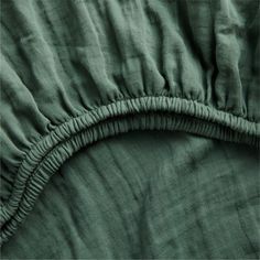 an image of the back side of a bed with green sheets and ruffles