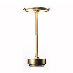 a gold colored table lamp on a white background with the light reflecting off it's base