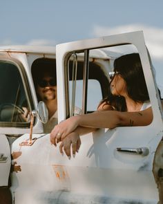 a man and woman sitting in the driver's seat of an old truck