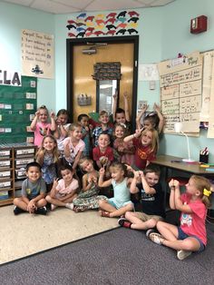 a group of children sitting on the floor in front of a classroom