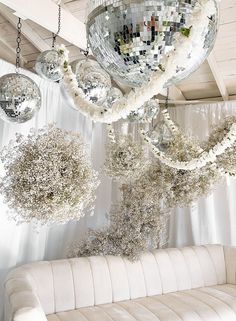 white couches and chandeliers hanging from the ceiling in front of a mirror ball