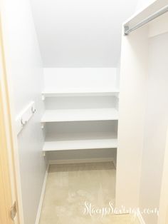 an empty walk in closet with white shelving