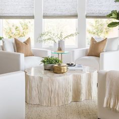 a living room filled with white furniture and lots of plants on top of the table