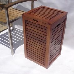 a wooden trash can sitting on top of a white floor next to a metal chair