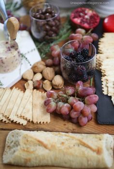 grapes, almonds and crackers are on a wooden table with other food items