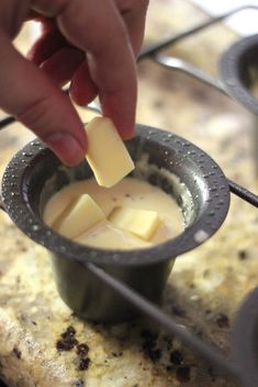 a person dipping cheese into a small cup