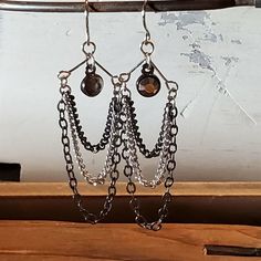 a pair of earrings with chains hanging from them