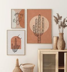 three framed art pieces hang on the wall next to a basket and vase with plants in it