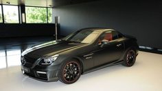 a black sports car parked in an empty room with lots of windows on the wall