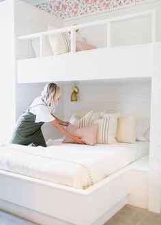 a woman in white shirt and green skirt working on a bed