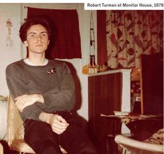 a man sitting on top of a chair in a living room next to a window