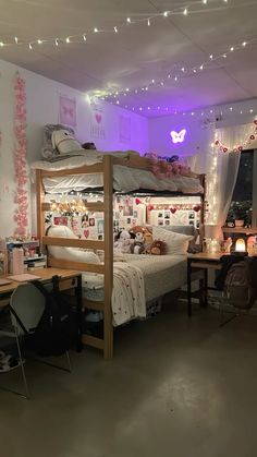 a room with bunk beds, desks and lights on the ceiling is lit by fairy lights