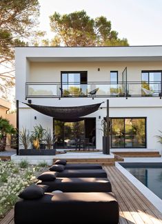 a house with a pool in front of it and lots of plants on the lawn