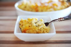 a bowl of macaroni and cheese with a spoon in it on a wooden table