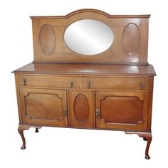 an old fashioned wooden dresser with mirror on it's top and side panels,